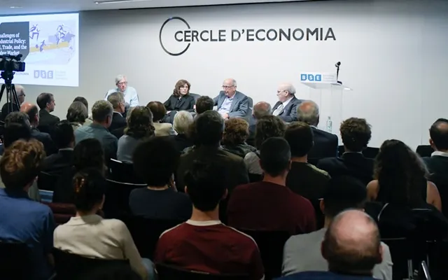 Panelists speak in front of a packed auditorium