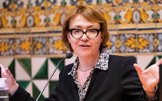 Ekaterina Zhuravskaya gestures while speaking. In the background there is a wall covered in Modernist tiles
