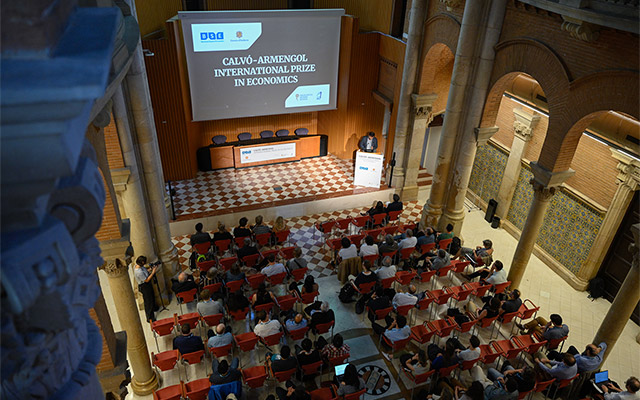 Aerial view of the Aula Magna where we can see the decorative columns, floor tiles, and the audience below during the event