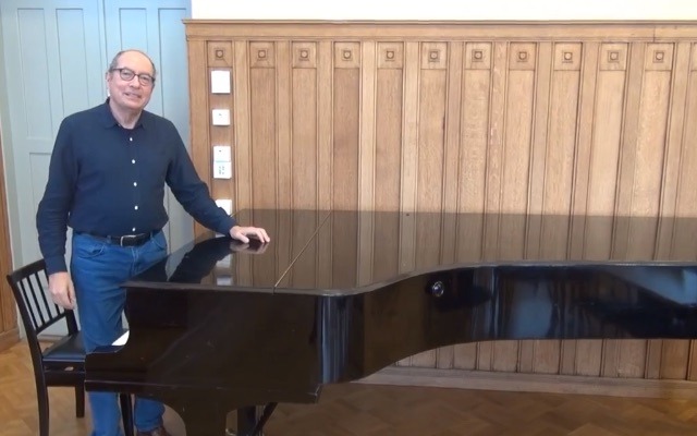 Michael Greenacre standing next to a grand piano in Helsinki