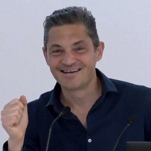 Nicola Gennaioli speaking in front of a microphone
